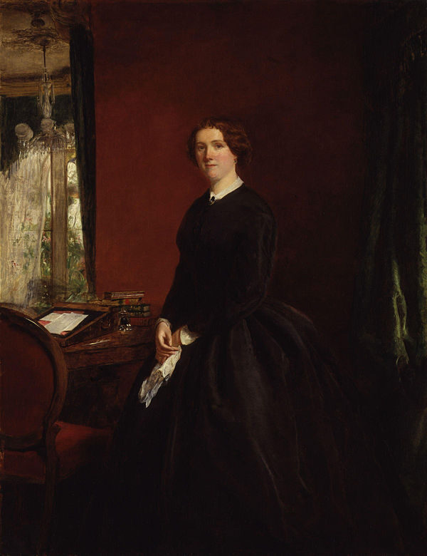 A painted portrait of Mary Elizabeth Braddon standing beside her writing desk