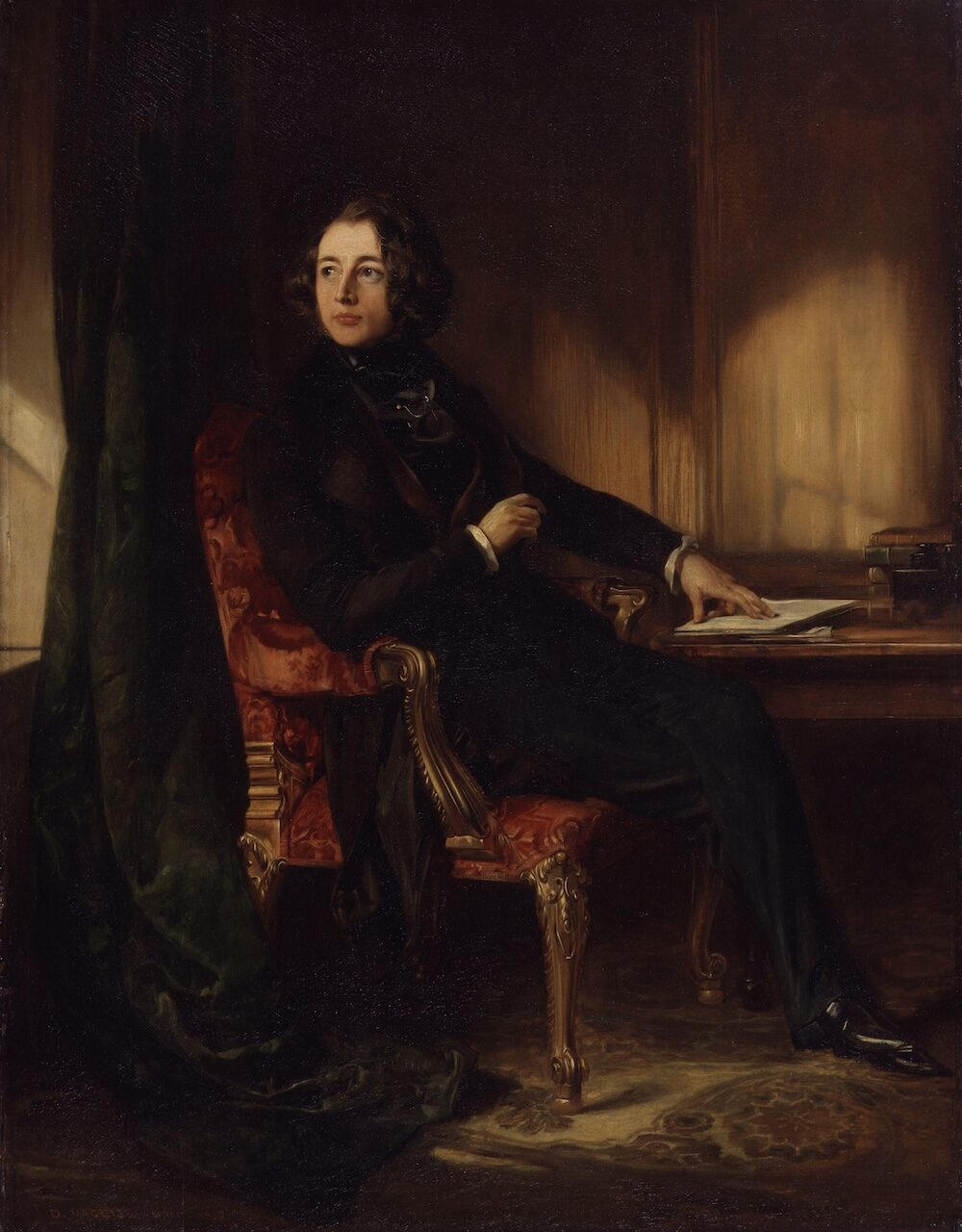 A painted portrait of a young Charles Dickens seated at his desk