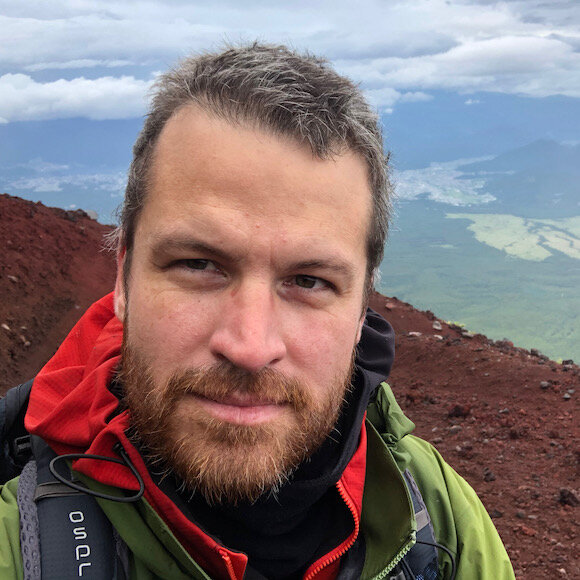 Peter Armstrong, on a mountainside in a red and green jacket
